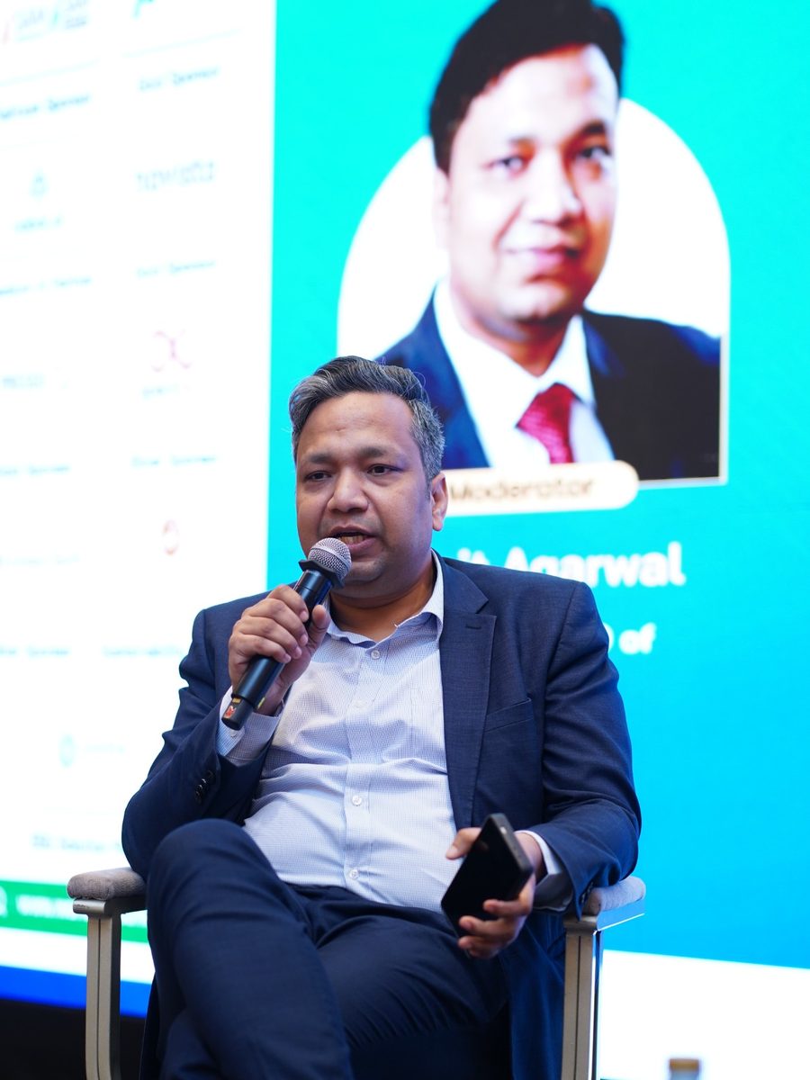Sumit Agarwal speaking as moderator, with his moderator card on the screen behind him